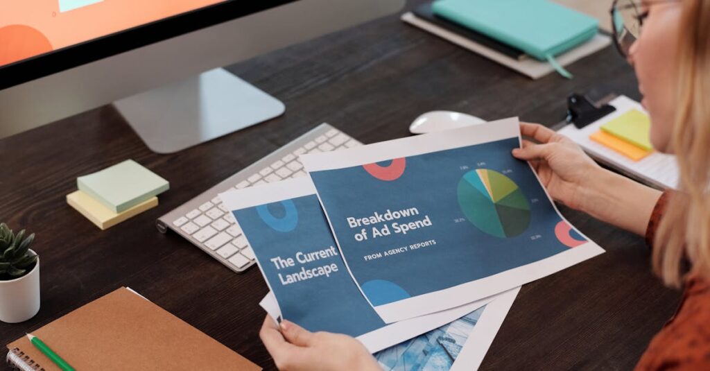 A businesswoman reviews marketing documents with charts at her desk, featuring a computer and office supplies.