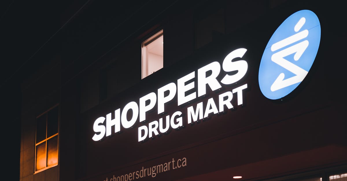 Brightly lit Shoppers Drug Mart sign on building exterior at night, urban setting.